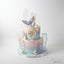 A two-tiered butter cream cake designed to look like a mermaid tail, with blue and pink layers, decorative underwater themed elements, and the words 'Happy Birthday' on the top tier.