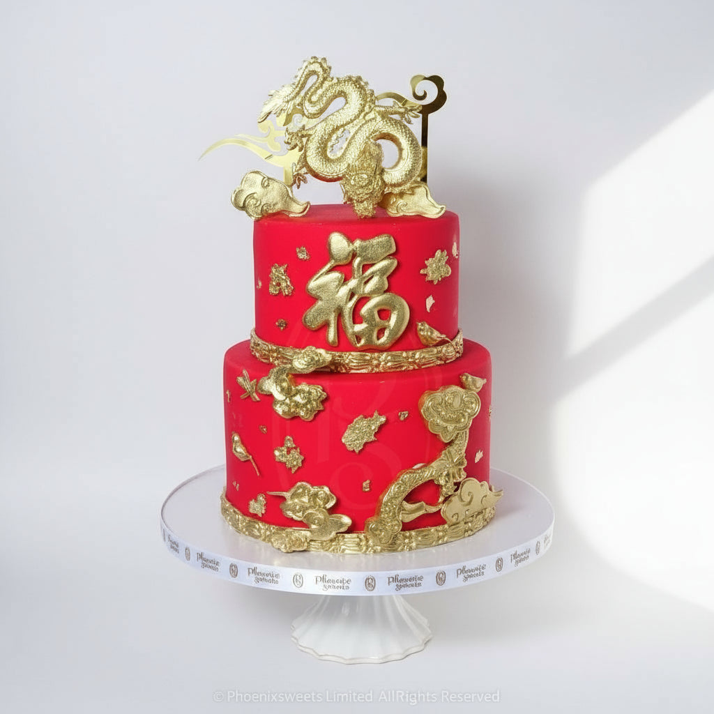 A two-tiered fondant cake decorated with gold dragon designs and Chinese characters, primarily in red and gold colors, displayed on a white cake stand.